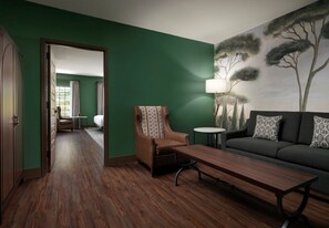 A room with a green wall, a sofa, a chair, a table, and a lamp. - Dellshire Resort (Wisconsin Dells)