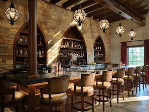 Un'area bar con pareti in pietra, bancone in legno e diversi sgabelli da bar.