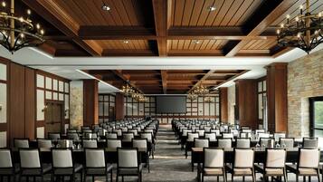 A conference room with rows of chairs, a large screen, and chandeliers.