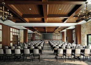 Un salón de conferencias con filas de sillas, una pantalla grande y candelabros.