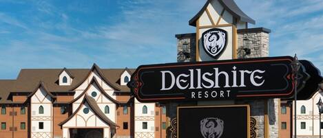 Een hotelingang met een bord waarop 'Dellshire Resort' staat en een logo erboven.