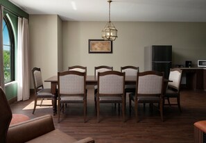 A dining area with a table and chairs, a chandelier, a framed picture, and a kitchen area with appliances. - Dellshire Resort (Wisconsin Dells)