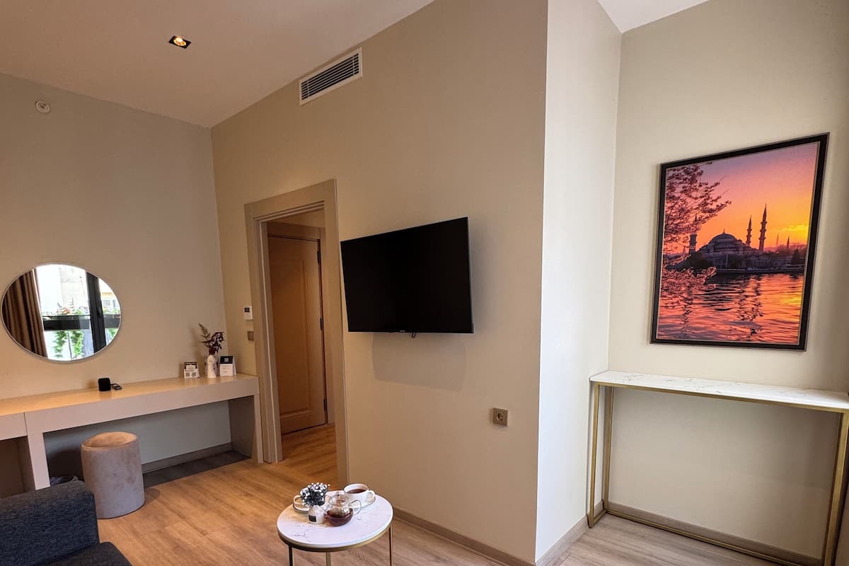 A modern living room with a flat-screen TV, a round mirror, a coffee table, and a sofa.