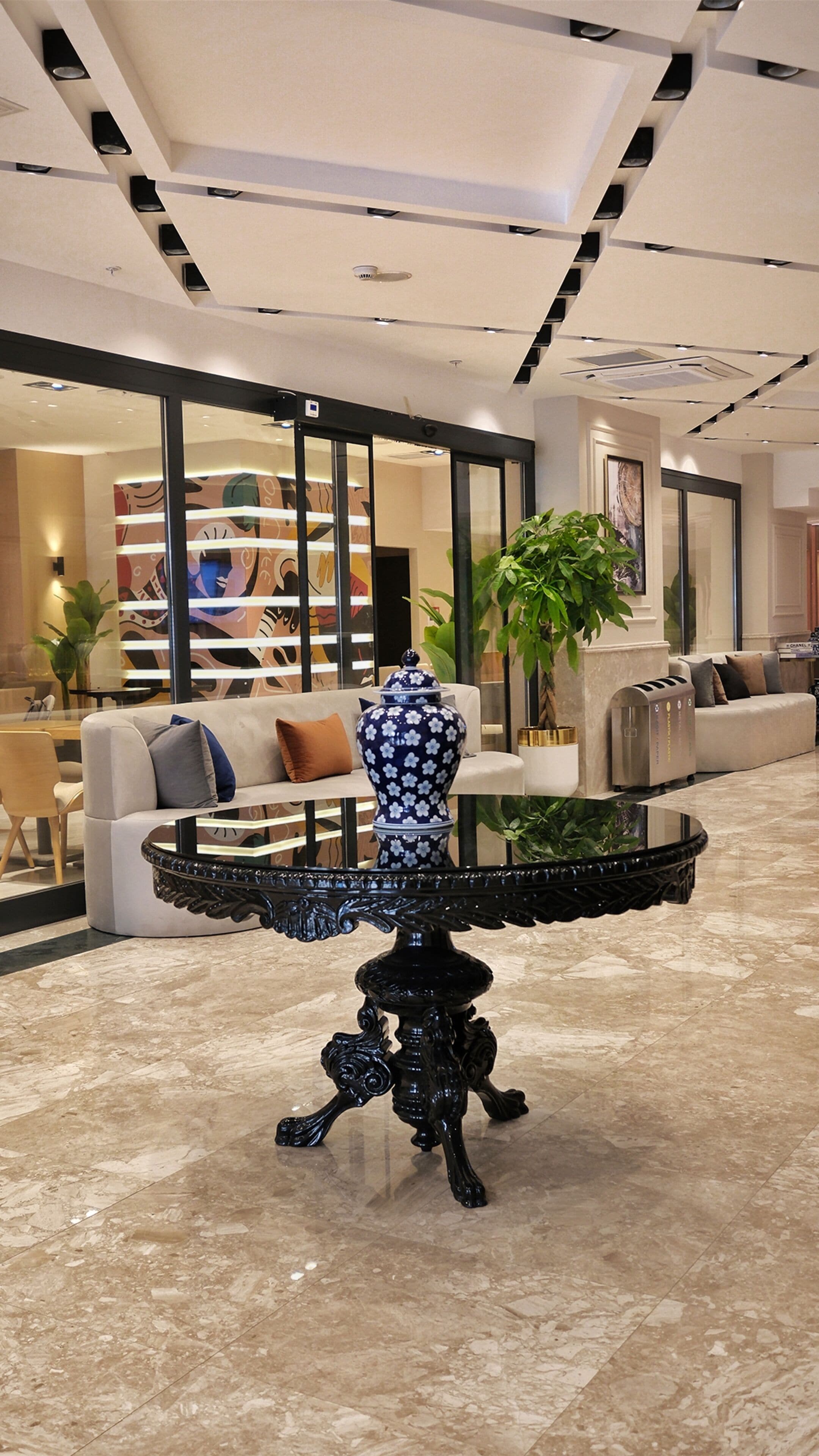 A modern lobby with a round table, sofas, and a staircase.