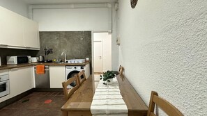 Una cuina funcional amb taula de menjador, cadires, microones i rentapeus.