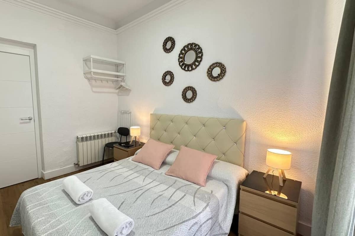 A neatly arranged bedroom with a bed, bedside tables, a wardrobe, and wall decorations.