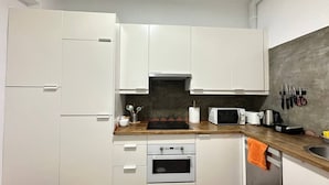 A compact kitchen with white cabinets, a microwave, a toaster, and a coffee maker. - Habitaciones Manuela (Madrid)