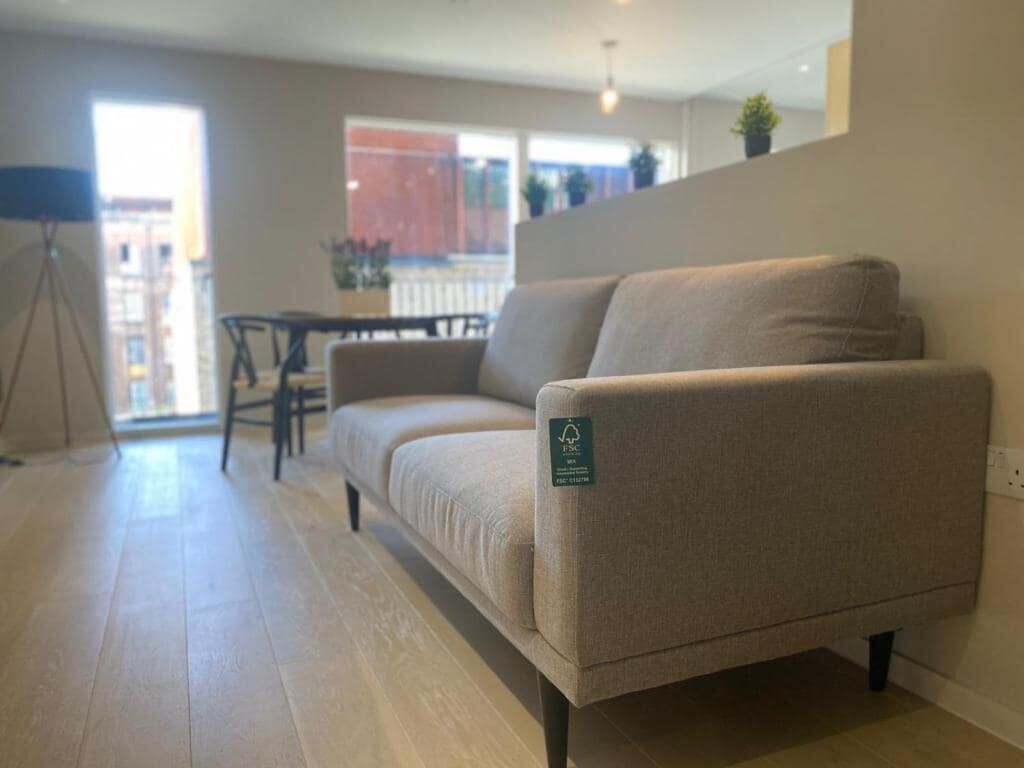 A modern living room with a beige sofa, a small table, and a tripod lamp.