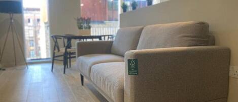 A modern living room with a beige sofa, a small table, and a tripod lamp.