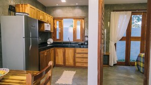 A compact kitchen with wooden cabinets, a refrigerator, and a microwave. - La Casina Jericoacoara (Jijoca de Jericoacoara)