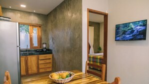 A kitchen with wooden cabinets, a refrigerator, and a dining table with a bowl of fruit. - La Casina Jericoacoara (Jijoca de Jericoacoara)