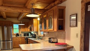 Une cuisine avec des meubles en bois, un grand îlot central doté de tabourets, des appareils électroménagers en acier inoxydable et un luminaire suspendu.