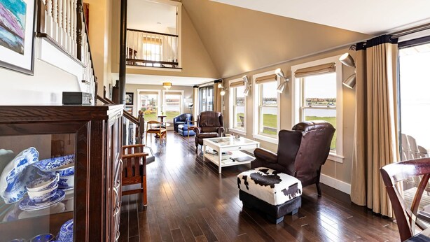 A spacious living area with a high ceiling, a staircase, and a view of the outdoors.