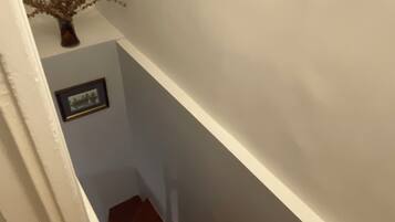 Una escalera de madera con una pared blanca y un cuadro enmarcado.