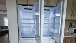 Eine moderne Küche mit einem eingebauten, doppelwandigen Kühlschrank, Holzschränken und einer Mikrowelle auf der Arbeitsplatte.