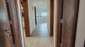 Ein Korridor mit Holztüren, Fliesenboden und Deckenleuchte.