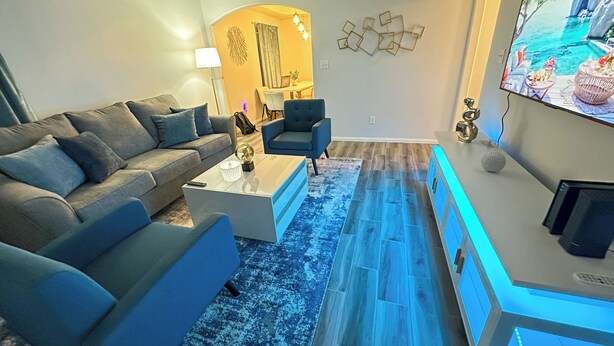 Una sala de estar moderna con sofá, mesa de centro y mueble para televisión.