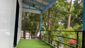 A balcony with artificial grass, metal railing, and tropical plants. - Blue Shore Pavilion (Sihanoukville)