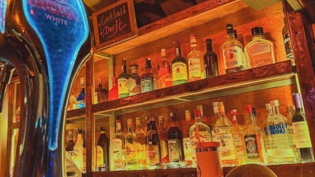 A bar area with shelves of liquor bottles and a neon sign for 'Anchor White'. - Blue Shore Pavilion (Sihanoukville)
