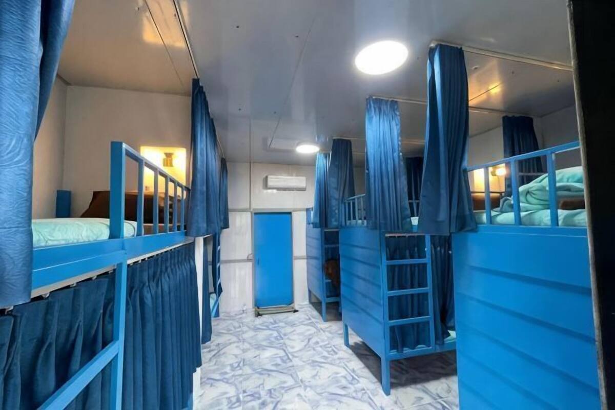 A room with bunk beds, a small desk, and a window.