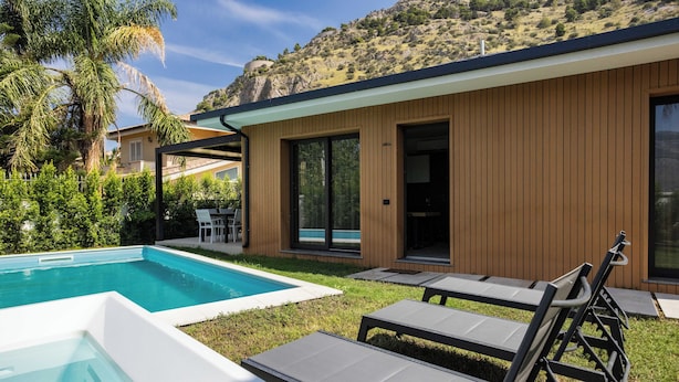 Een modern huis met een zwembad, terras en uitzicht op een glooiend landschap.