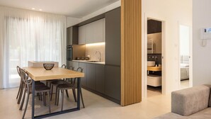 A modern kitchen with dark cabinets, a wooden dining table, and chairs. - Luxury Villa Artemis (Palermo)