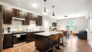 A modern kitchen with dark wood cabinets, a granite countertop, and a central island with bar stools.