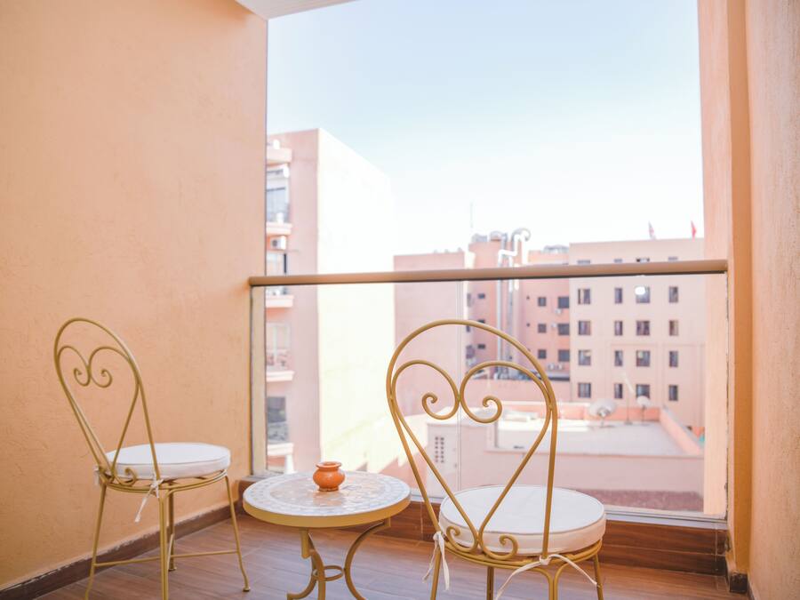 A balcony with two chairs and a small table, overlooking a cityscape.