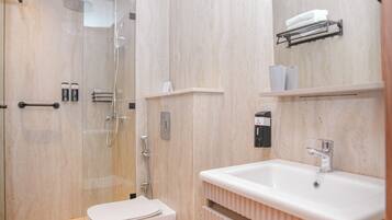 Une salle de bain moderne avec une douche à parois de verre, des toilettes blanches, un lavabo avec un miroir et un porte-serviettes.