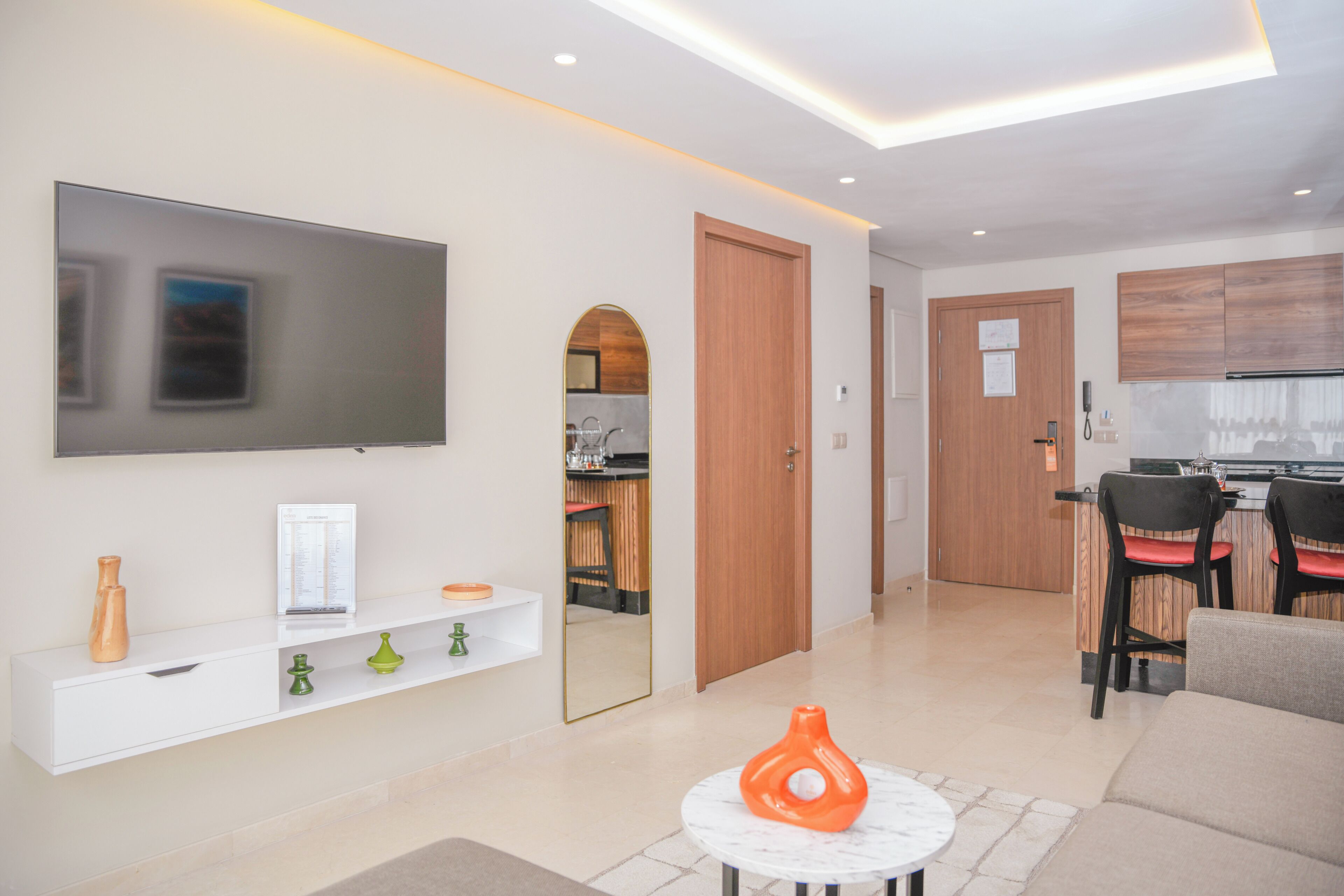 A modern living room with a flat-screen TV, a white console table, and a coffee table with a decorative vase.