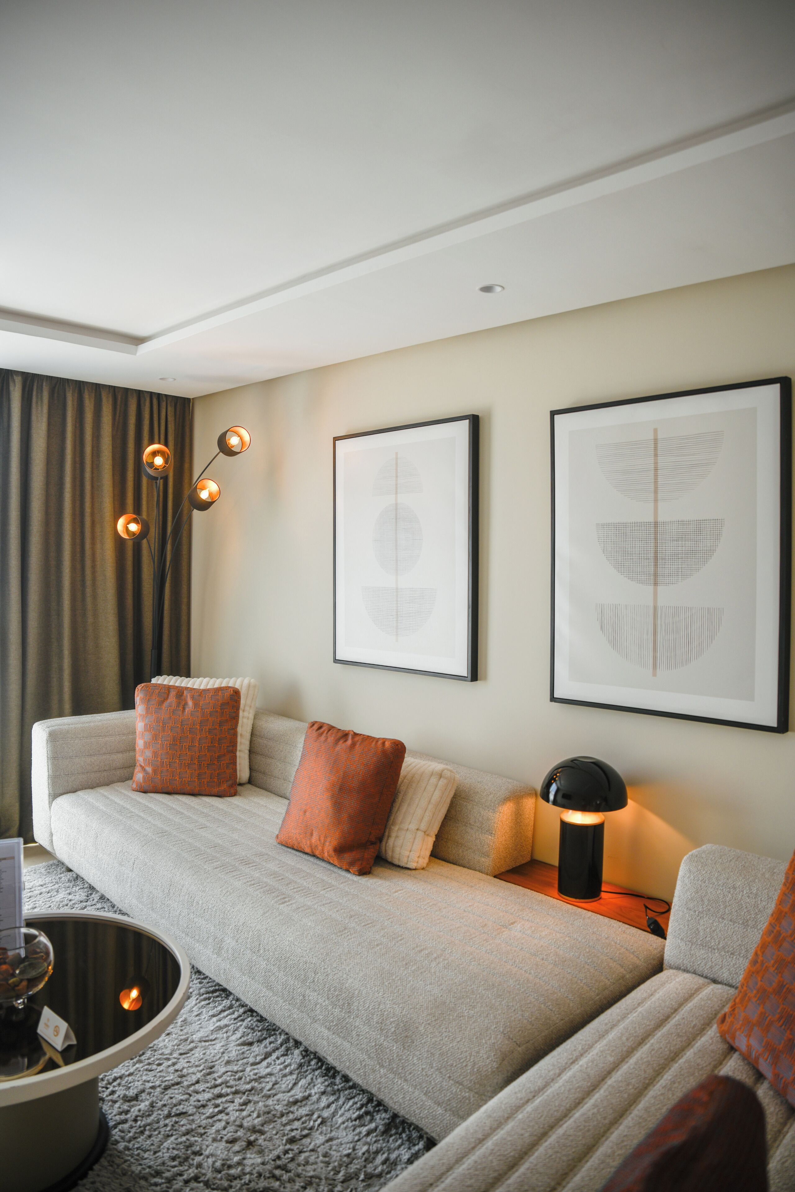 A modern living room with a sofa, two framed abstract artworks, a floor lamp, and a coffee table.