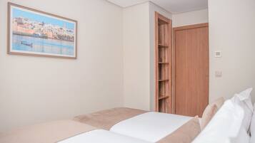 Ein Schlafzimmer mit einem Bett, einem Holzschrank und einem gerahmten Bild an der Wand.