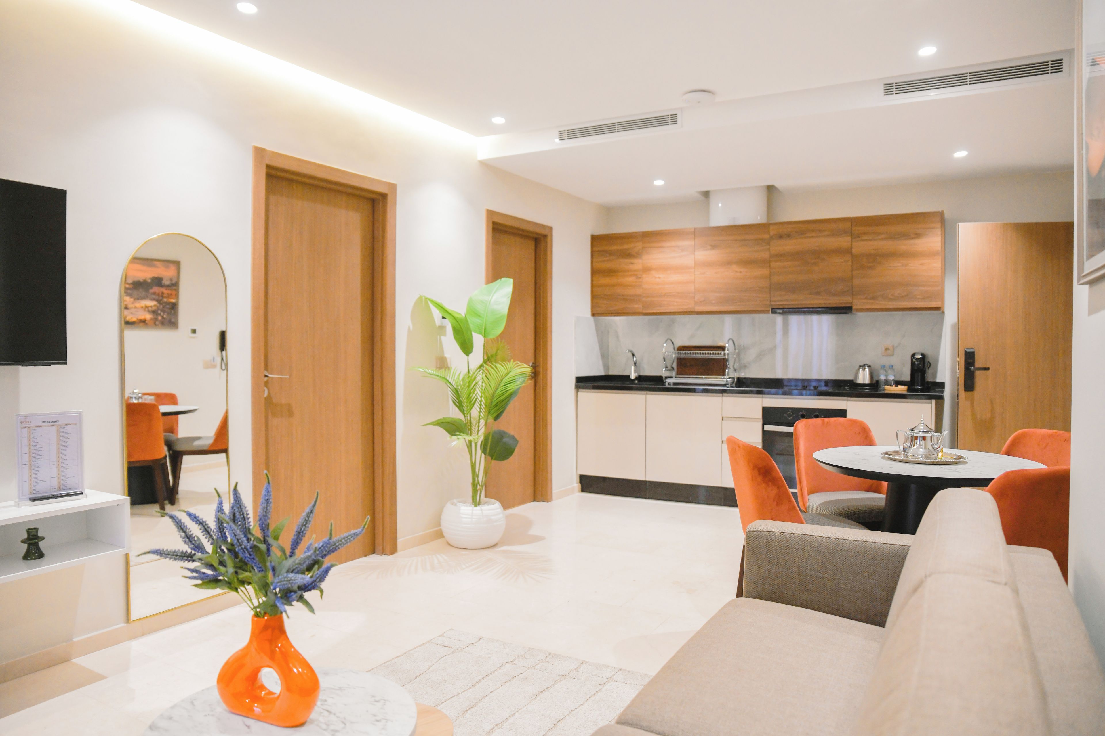 Una sala moderna con un sofá, una mesa de comedor y una cocina al fondo.