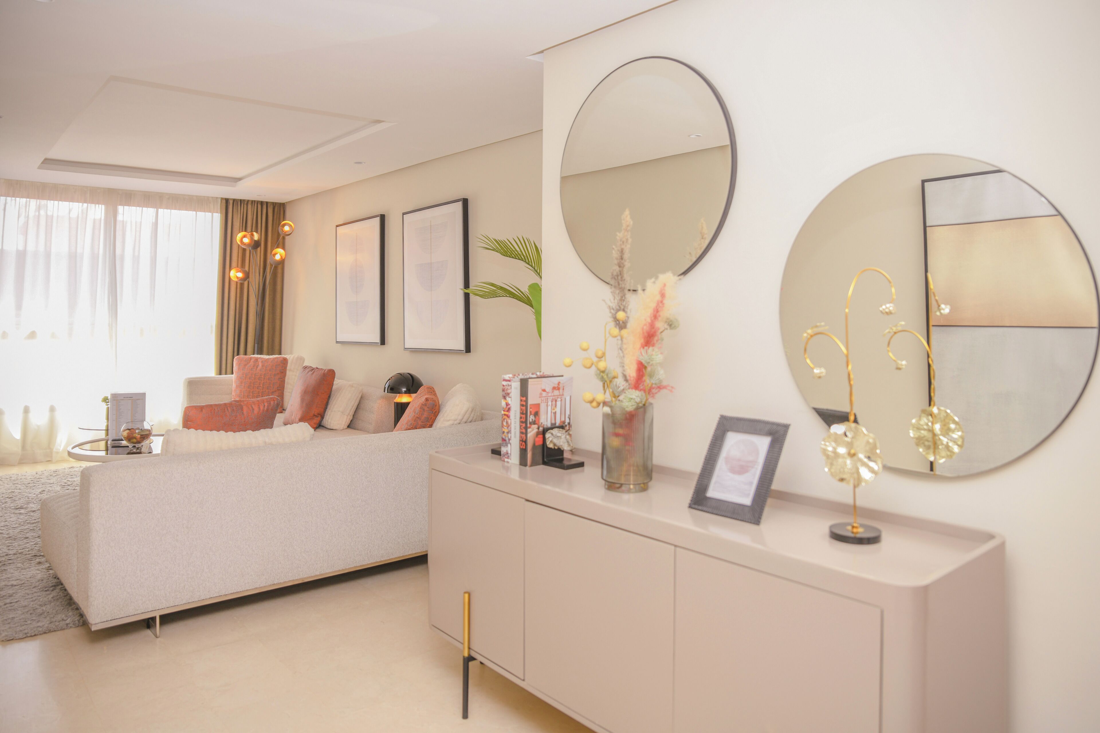 A modern living room with a sofa, a console table, and two wall-mounted mirrors.