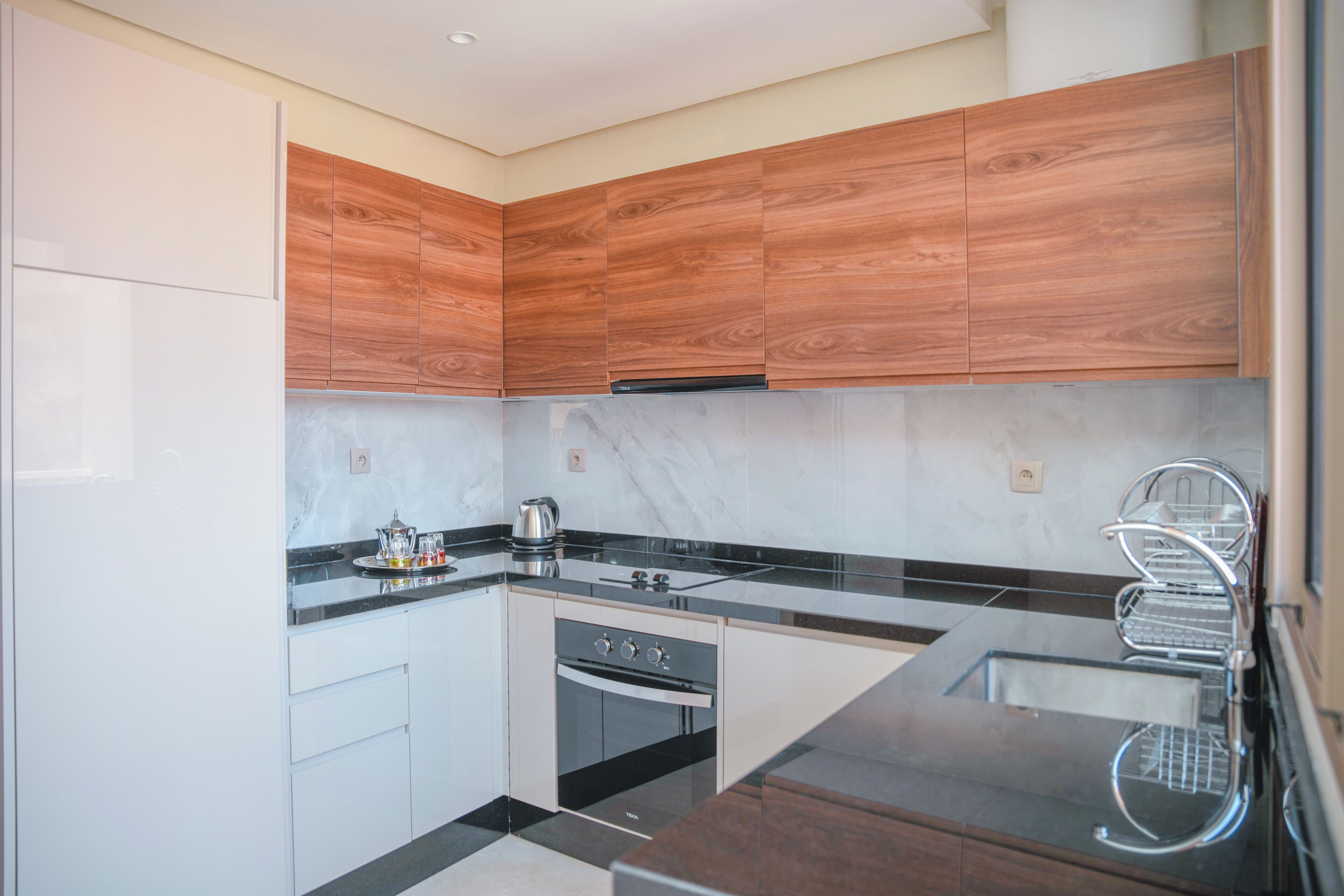 A modern kitchen with wooden cabinets, a black countertop, and a built-in oven.