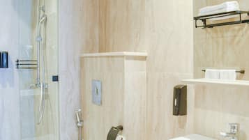 Un baño moderno con cabina de ducha de vidrio, inodoro blanco, lavabo con espejo y toallero.
