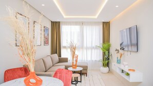 A modern living room with a sofa, a dining table, a TV, and decorative plants. - Résidence Eden Marrakech (Marrakech)