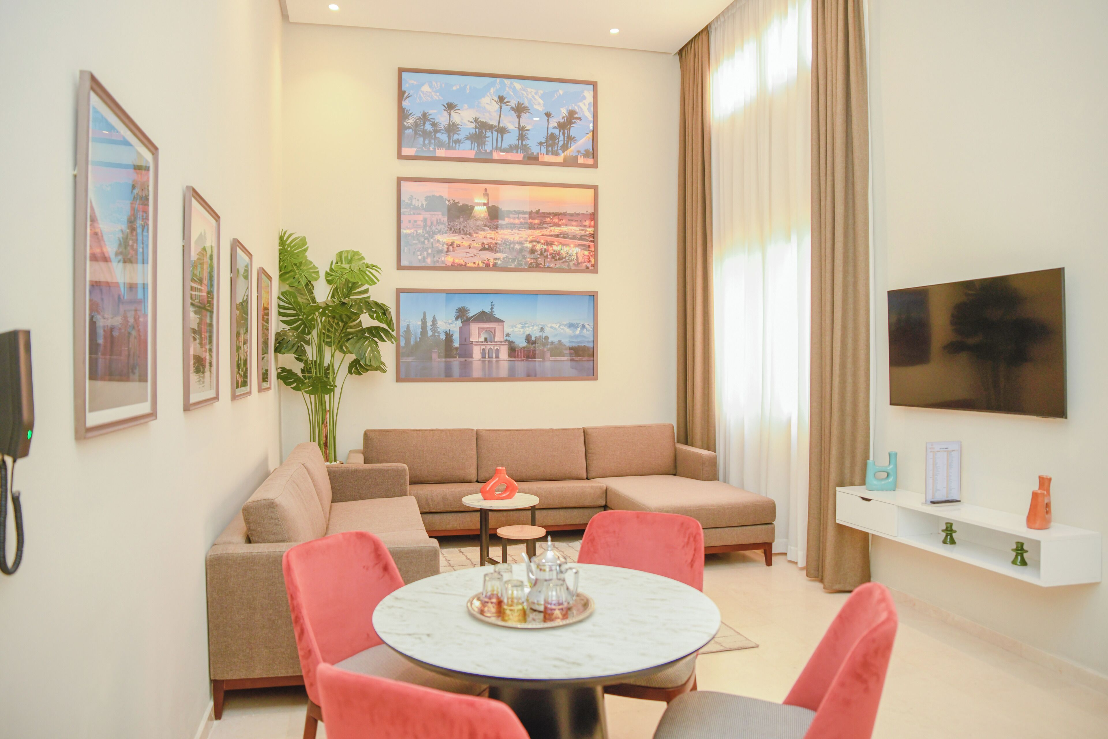A living room with a beige sofa, a round coffee table, and a TV mounted on the wall.