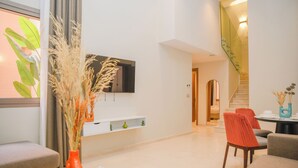 A modern living room with a flat-screen TV, a sofa, a coffee table, and a dining area with chairs. - Résidence Eden Marrakech (Marrakech)