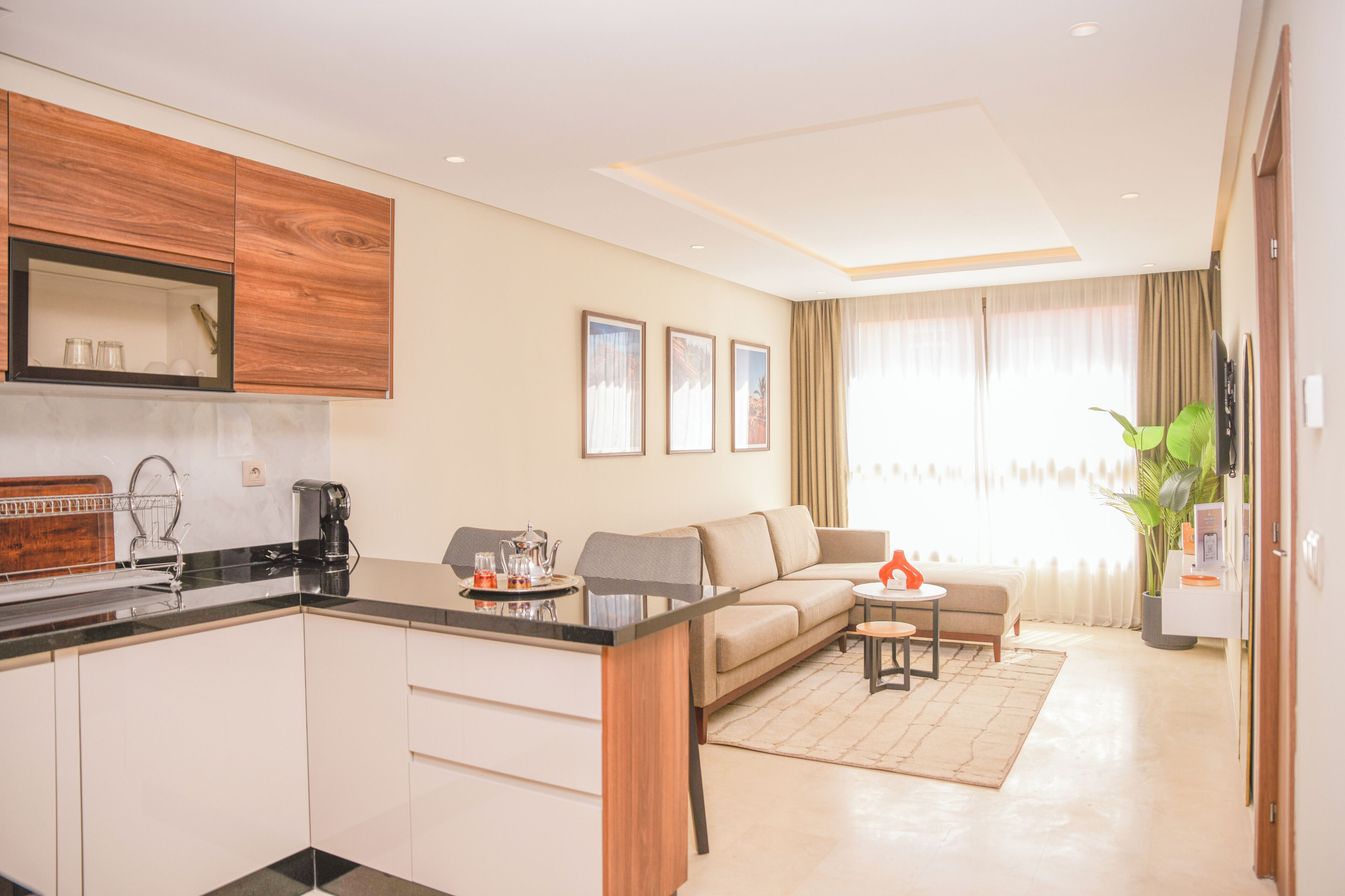 A modern kitchen with a built-in oven, a coffee machine, and a dining area with a sofa and a small table.