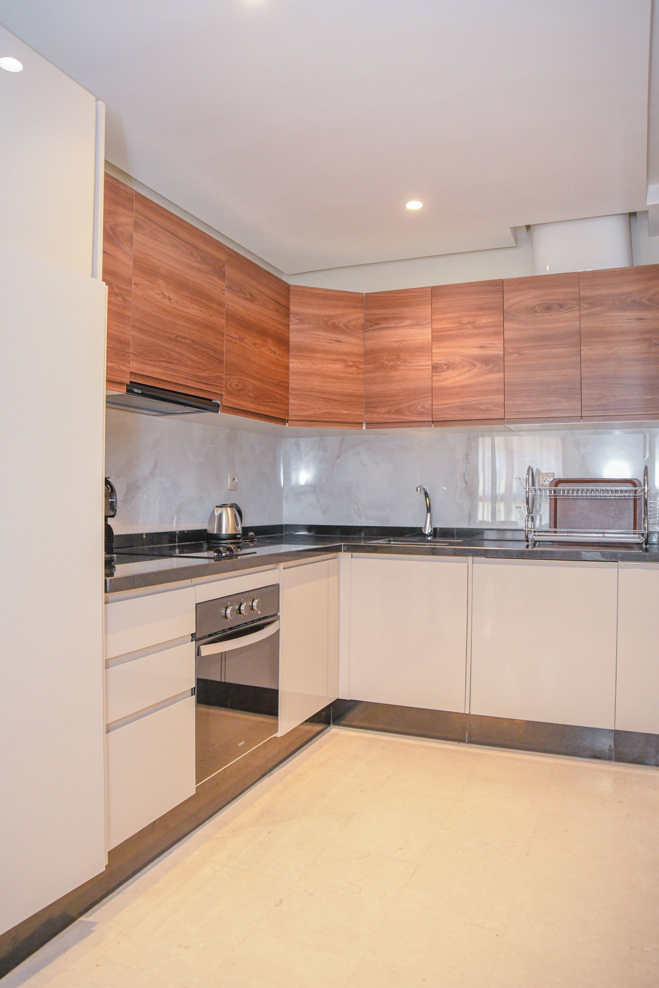 A modern kitchen with white cabinetry, a stainless steel range, and a black countertop.
