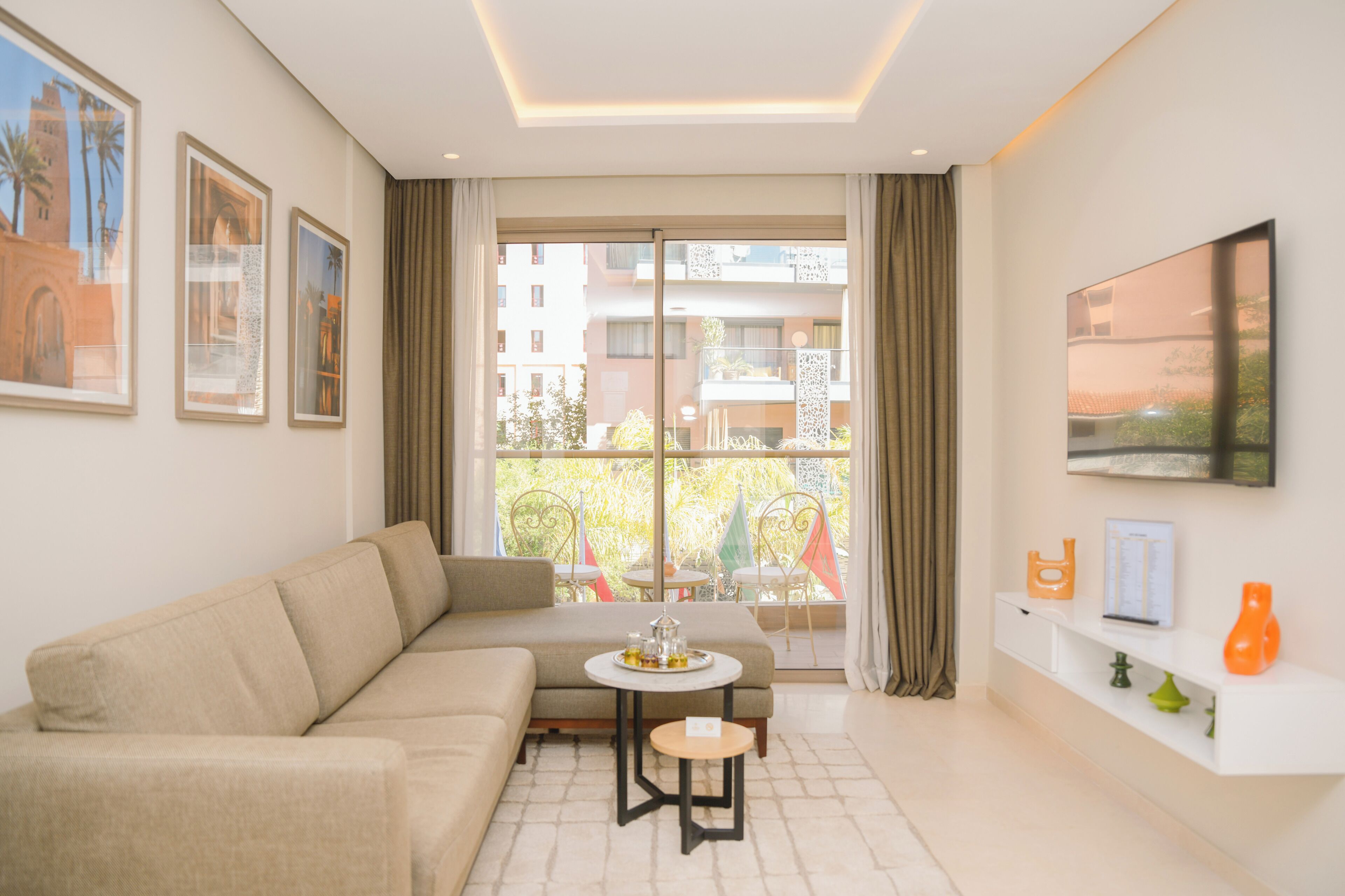 A modern living room with a sofa, a small round table, and a TV mounted on the wall.