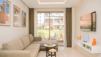 A modern living room with a sofa, a small round table, and a TV mounted on the wall.