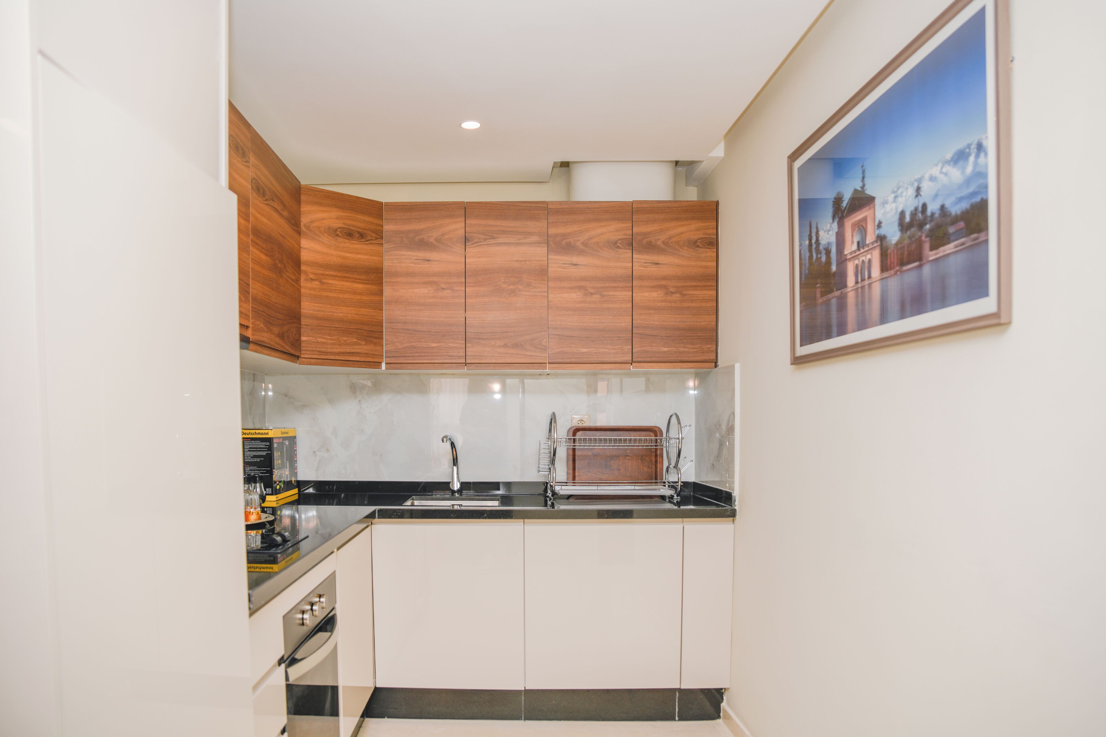 A kitchen with wooden cabinets, a black countertop, a sink, and a toaster.