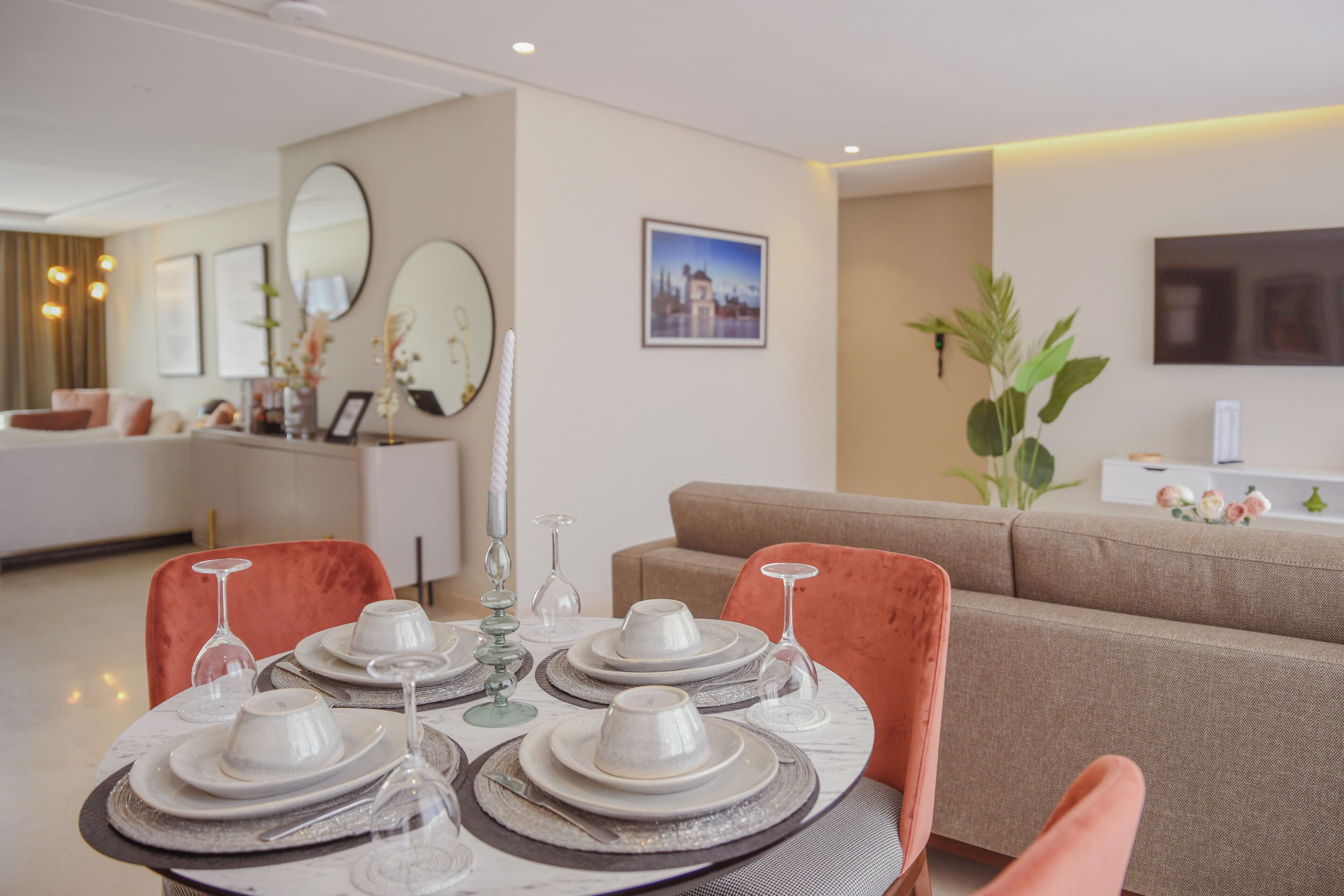 Un coin repas avec une table dressée pour quatre personnes, un canapé et un téléviseur en arrière-plan.