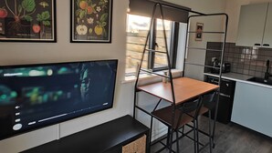 Uma cozinha moderna com área de refeições, televisão fixada na parede e janela com persianas.