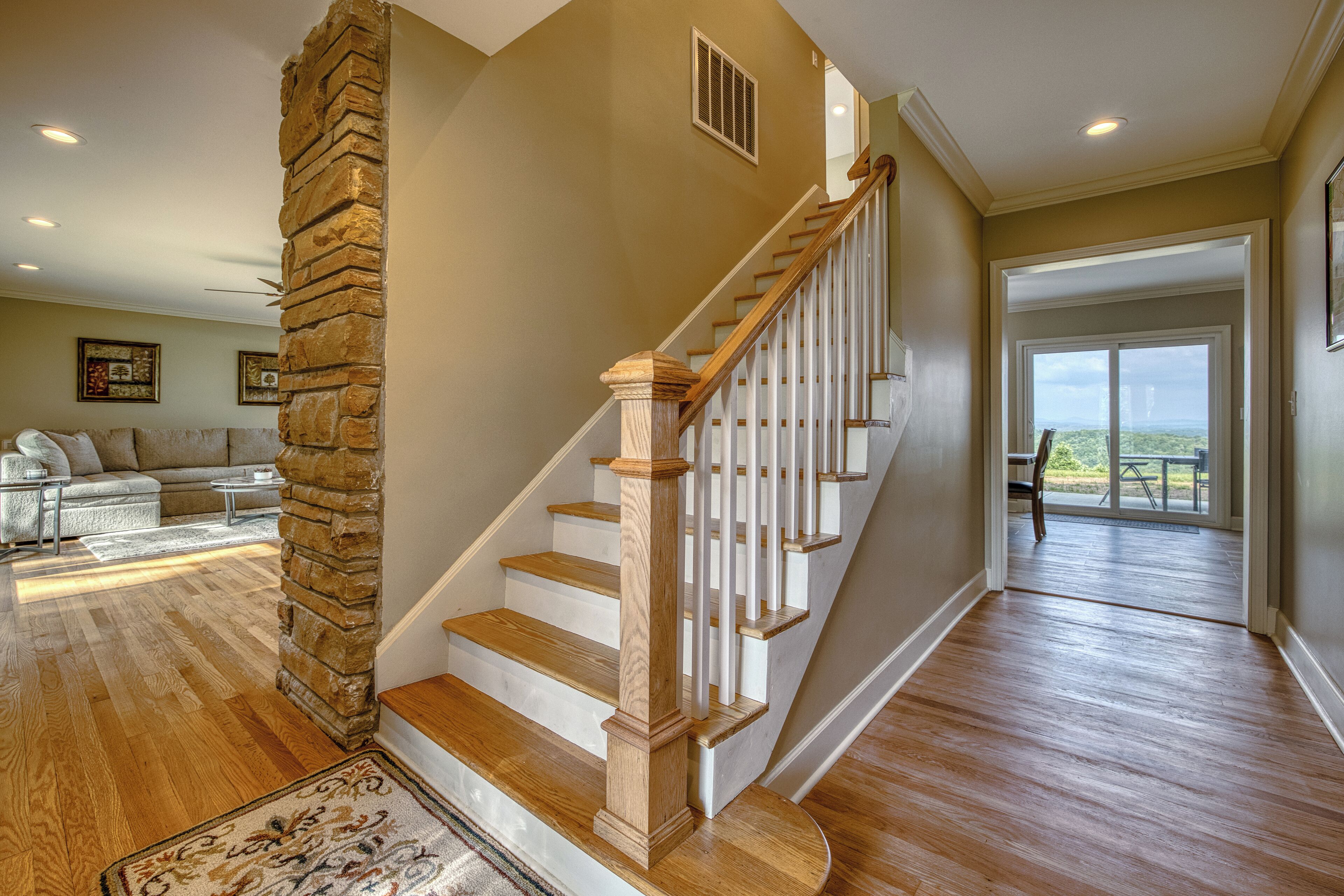 A staircase with wooden steps and white railings, leading to a balcony with a view.