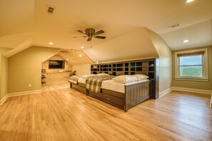 A bedroom with a sloped ceiling, a bed, built-in shelving, a ceiling fan, and a window with a view. - Escape to Hilltop Estate—a newly renovated 5BR, 3BA mountain retreat (Blue Ridge)