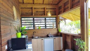 Eine kleine Küche mit Holzwänden, einem Spülbecken, einer Mikrowelle und einem kleinen Kühlschrank.