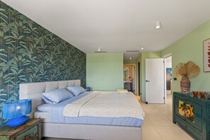 A bedroom with a bed, a nightstand, a dresser, and a door leading to another room. - The Strand apartment 1A, 5 guests with pool and beach (Willemstad)